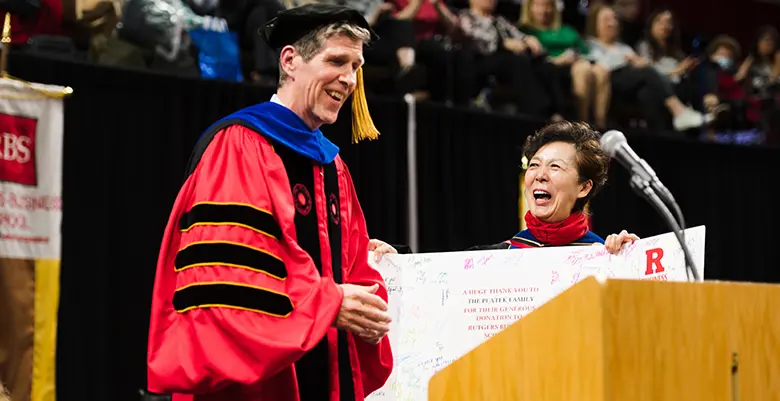 Rutgers Business School Dean Lei Lei presents commencement speaker Robert Platek with a giant thank you card.