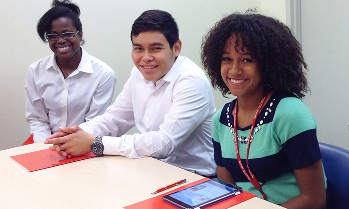 three students sitting and smiling at camera