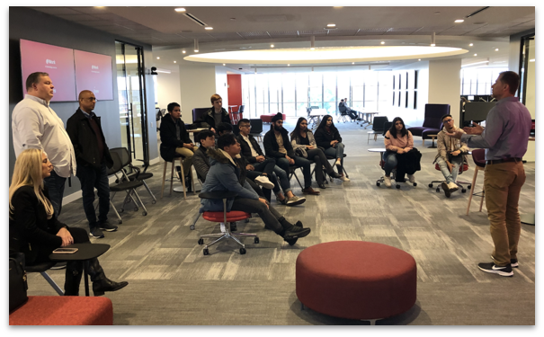 students listening to alumni speak at company