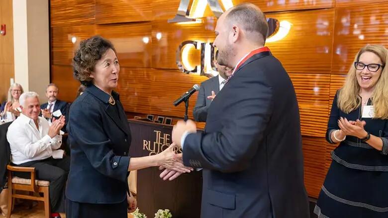 Alumnus Michael Pavlo receiving the Alumni Rising Star Award from Dean Lei Lei.