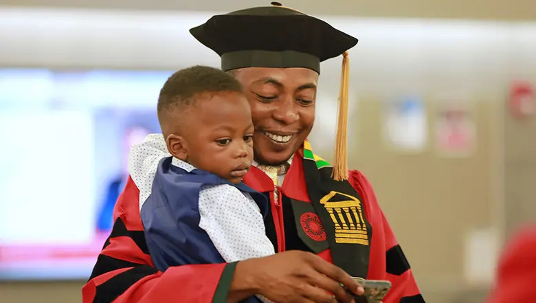 Graduating student Oluyinke Fadahunsi with his son.