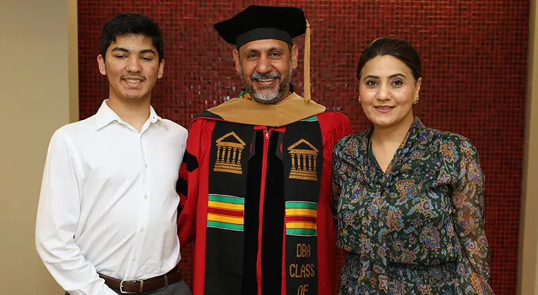 After the hooding ceremony, Rohit Chadha poses for photos with his wife and son.