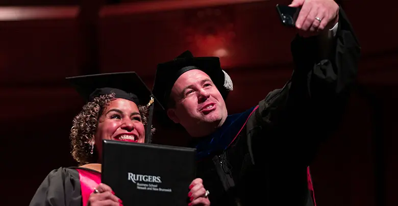 Rutgers Business School professor Rudi Lueschner takes a celebratory selfie with graduate Kathalina Tapia.