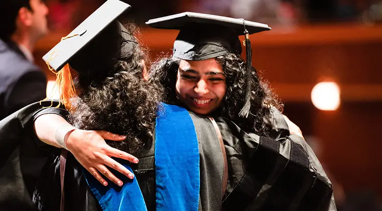 A graduate from the Master of Information Technology and Analytics Program hugs Professor Vijay Atluri.