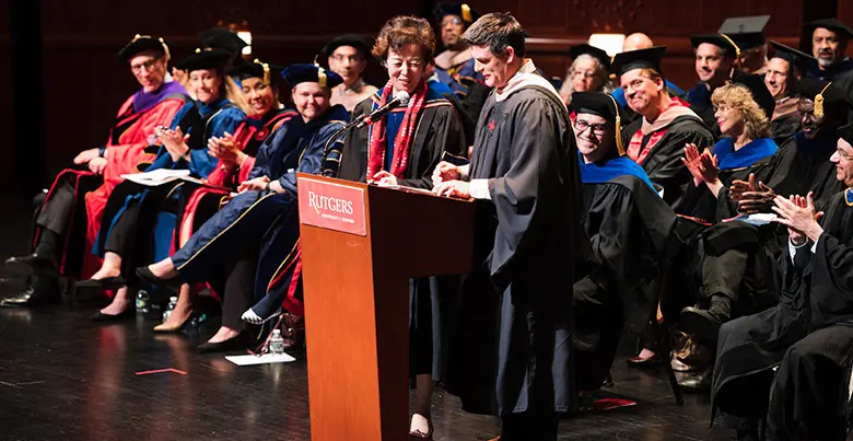 Convocation speaker Jeffrey Hermann stands with Dean Lei Lei at the podium.
