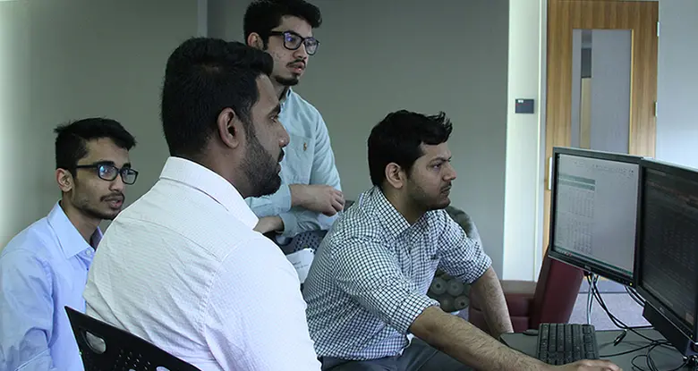 The MQF Risky Business team in front of a Bloomberg machine at Rutgers Business School.