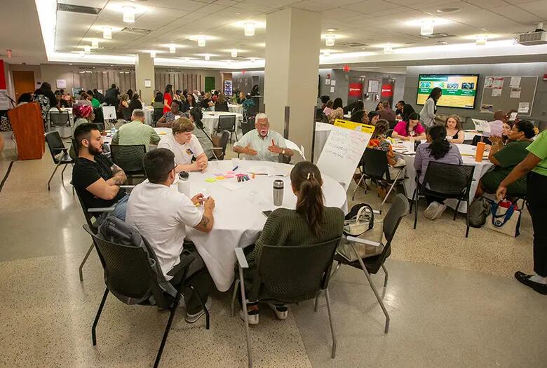 Photo shows conference attendees engaged in roundtable discussions.