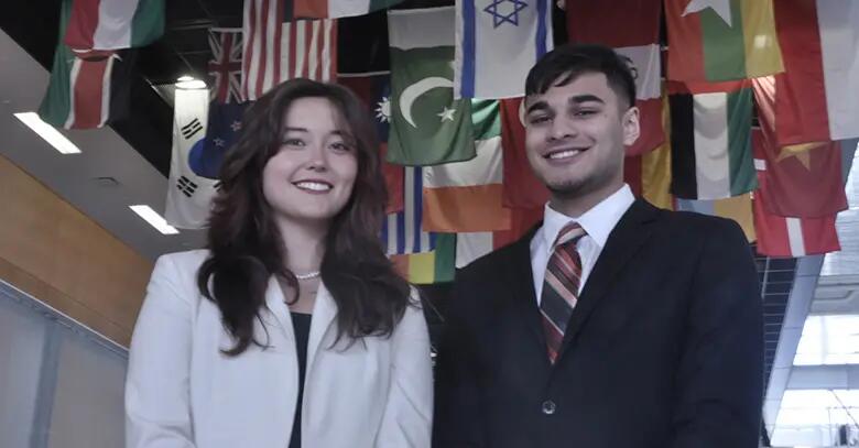 Two Rutgers Business School students pose on grand staircase at 100 Rock Building.