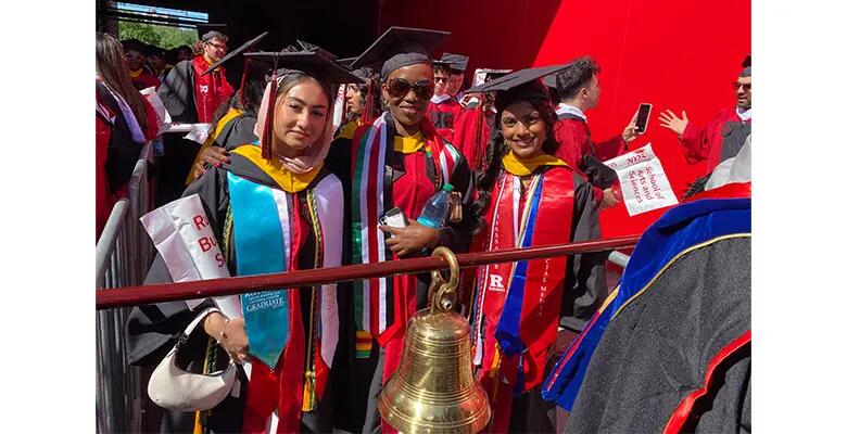 (From Left) Anum Fazal, Norah Were, and Neha Bhat lead the class of ’25 student procession carrying the Rutgers Business School Commencement Bell.