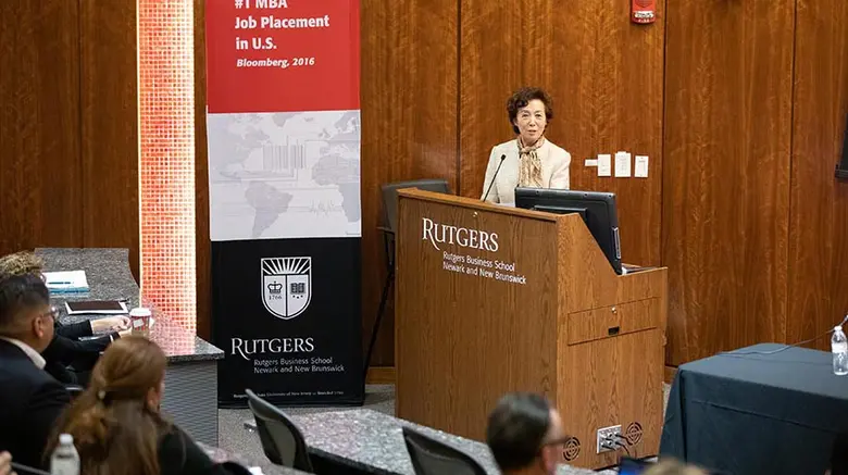 Rutgers Business School Dean Lei Lei stands at the podium, opening the seventh annual Business and Community Engagement Symposium.