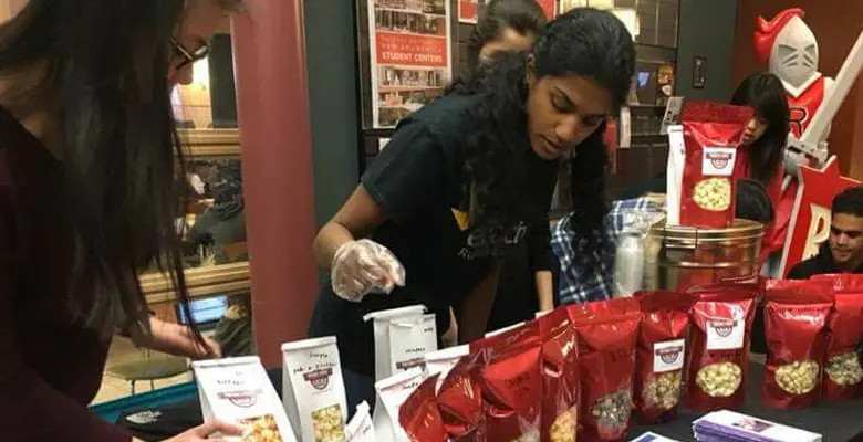 Enactus member, Sahana Premkumaar, center, works a Popcorn for the People table during a marketing event at Rutgers University’s Livingston campus student center. Photo: Courtesy of Enactus.