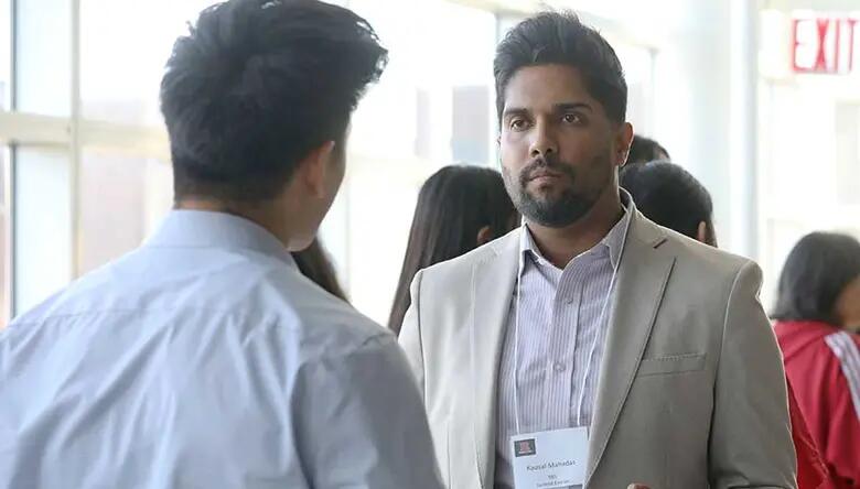 MBA student Kausal Mahadas speaks with a member of the audience.