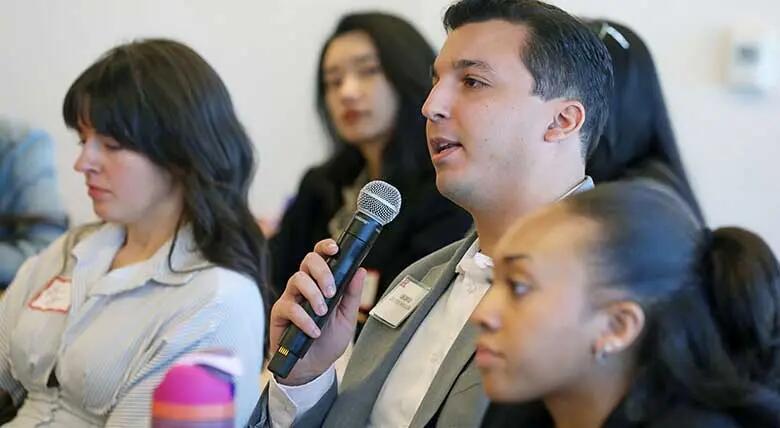 An audience member attending the annual marketing summit at Rutgers Business School poses a question to professionals participating in a panel discussion.