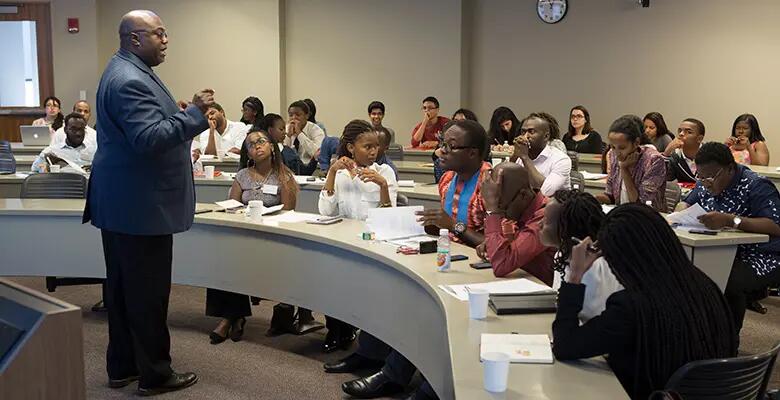 Professor Kevin Lyons during a session of the program that offered the high school students a chance to work alongside the Mandela Washington Fellows. In the Photo, Some of the fellows are seated in the first row of seats.