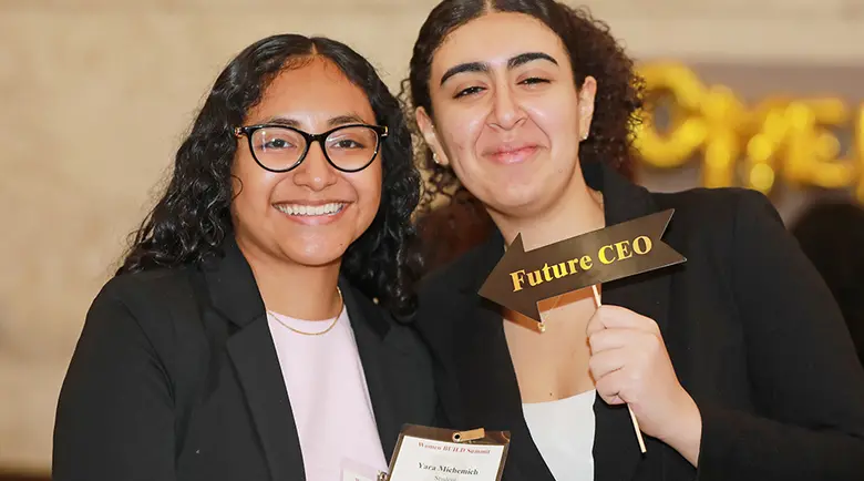 Two members of Women BUILD post for the camera with a Future CEO sign.