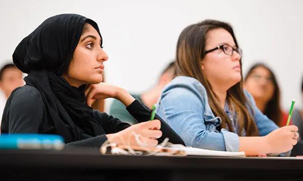 Undergraduate students taking notes in class.