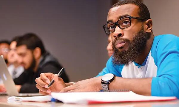 Undergraduate student taking notes in class.