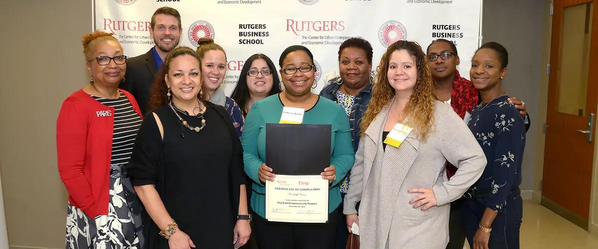 Participants taking a group photo. The woman in the middle is holding her completion certificate.