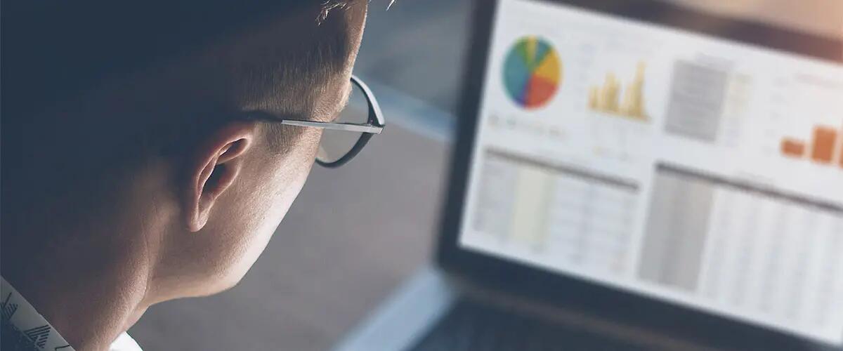 Credit: iStock - Man looking at a laptop screen with analytics data on it