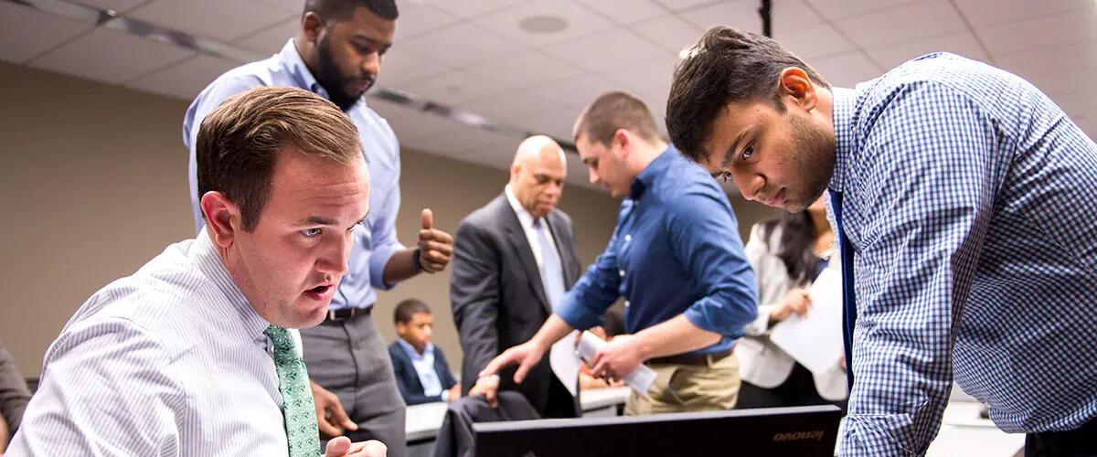 Students using a laptop while discussing in class