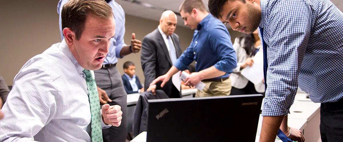 Students using a laptop while discussing in class
