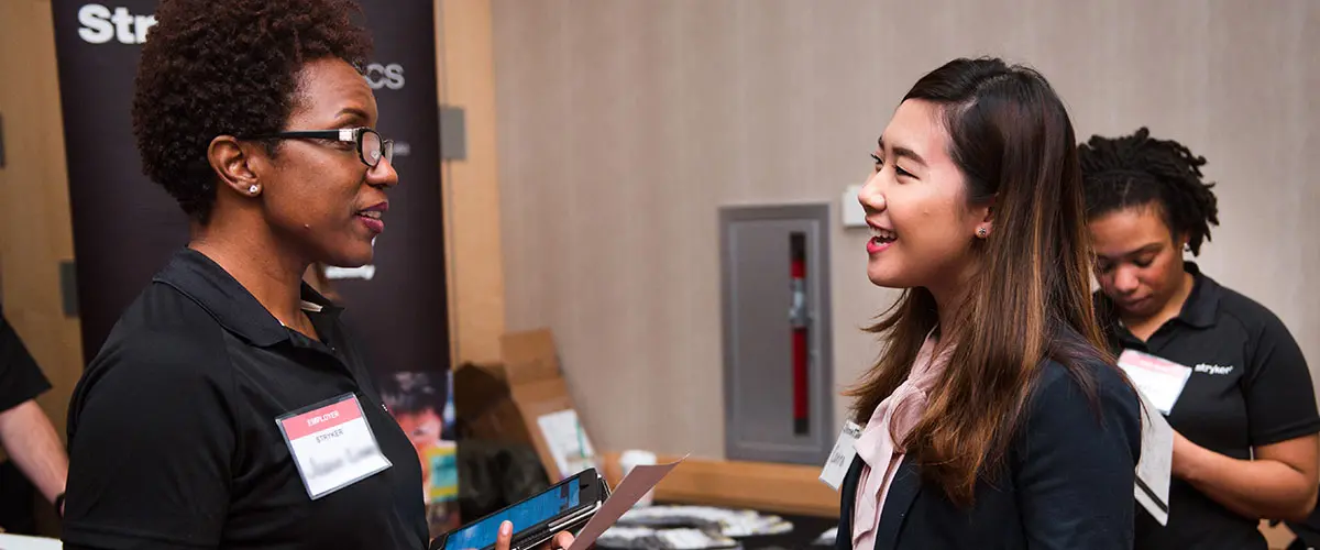 Student speaks with recruiter at career fair.