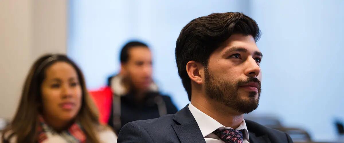 Male student in class wearing a suit with a focused look