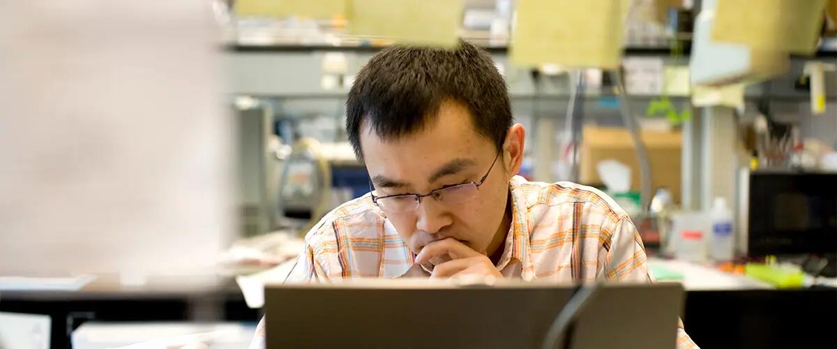 A male student in intense though as he looks over his work