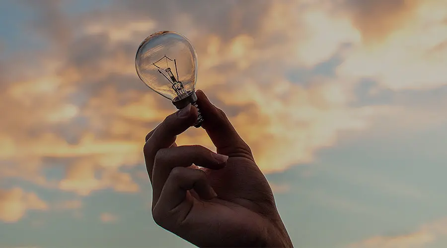 Innovation, person's hand holding a clear light bulb