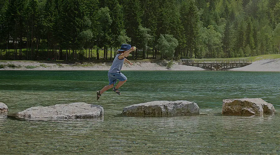 Child hopping across rocks in a stream.